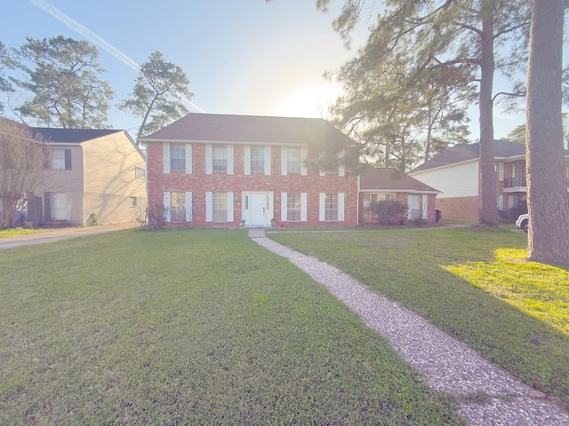 colonial-style house featuring brick siding and a front lawn