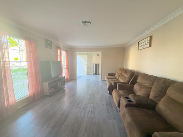 living area with wood finished floors, visible vents, and ornamental molding