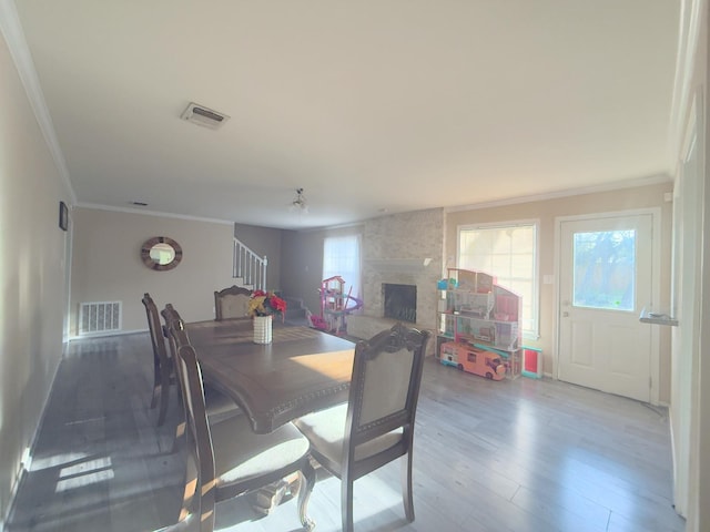 dining area featuring stairs, wood finished floors, visible vents, and a large fireplace