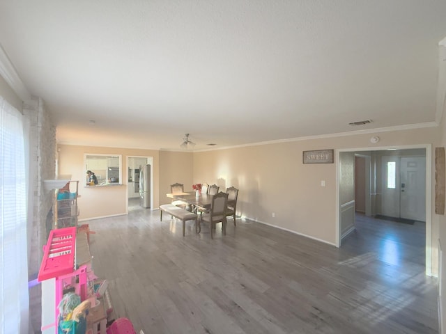 dining room with crown molding, wood finished floors, visible vents, and baseboards