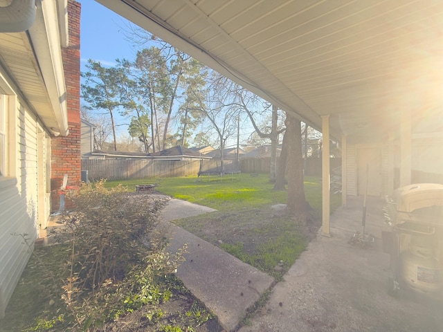 view of yard with a trampoline, a fenced backyard, and a patio area