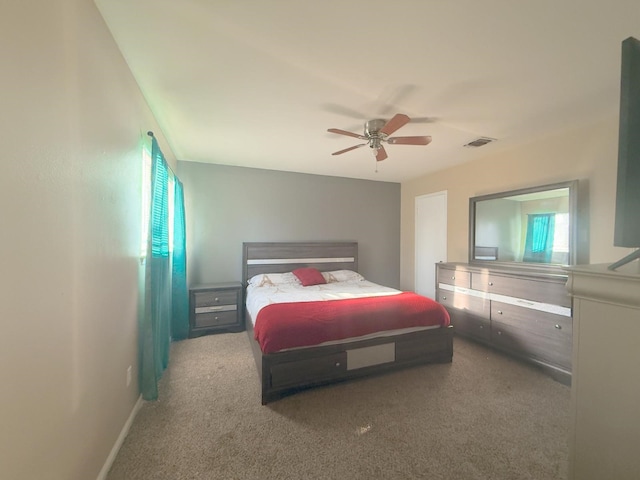 carpeted bedroom with visible vents, multiple windows, baseboards, and ceiling fan