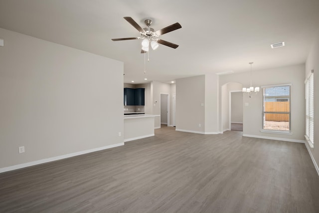 unfurnished living room with ceiling fan with notable chandelier, recessed lighting, baseboards, and wood finished floors