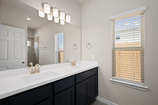 full bath with double vanity, a stall shower, baseboards, and a sink