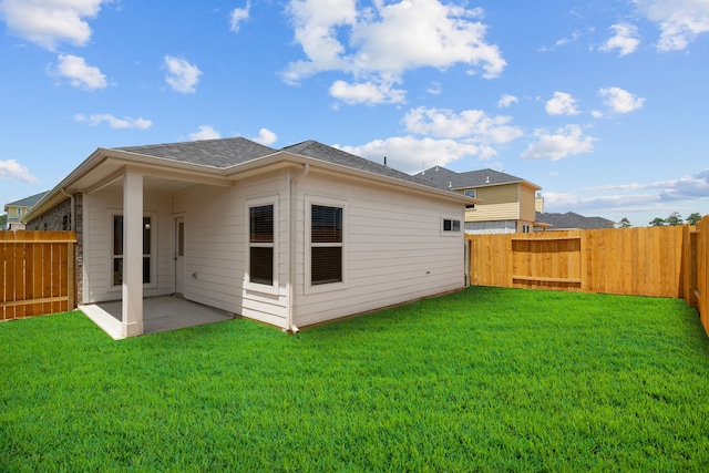 rear view of house with a lawn, a patio area, and a fenced backyard