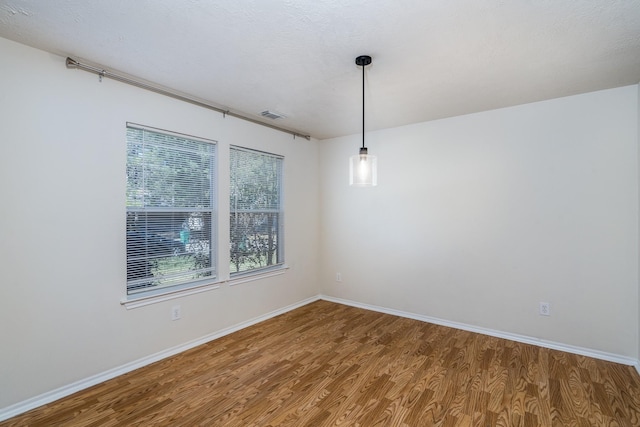 empty room with baseboards, visible vents, and wood finished floors