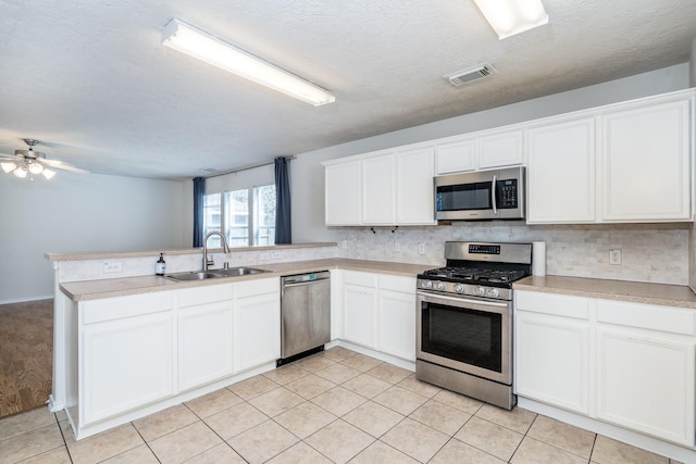 kitchen with visible vents, backsplash, appliances with stainless steel finishes, a sink, and a peninsula