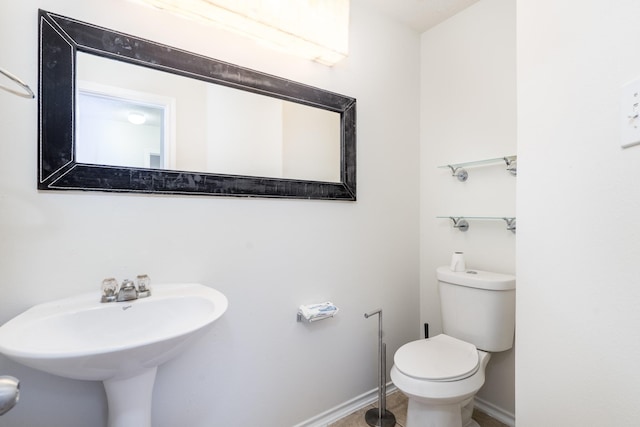 bathroom with toilet, baseboards, and a sink