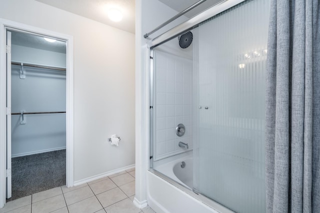 bathroom featuring shower / bath combo, baseboards, a walk in closet, and tile patterned floors