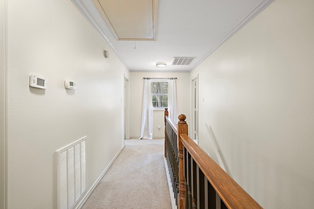 hallway with attic access, visible vents, ornamental molding, and light carpet