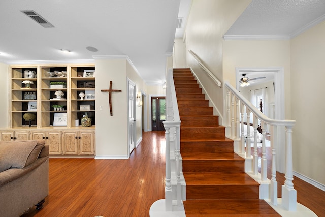 interior space with stairs, ornamental molding, wood finished floors, and visible vents