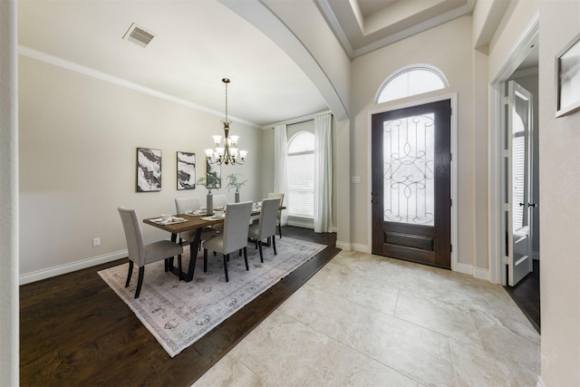 dining space featuring baseboards, visible vents, arched walkways, and crown molding