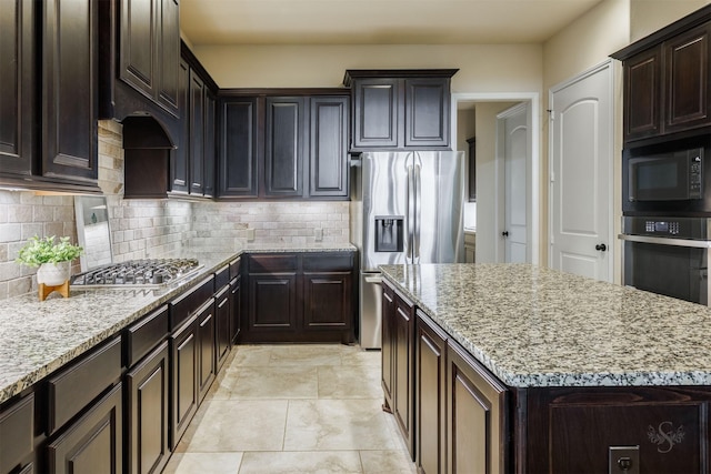 kitchen with a kitchen island, tasteful backsplash, light stone countertops, and stainless steel appliances