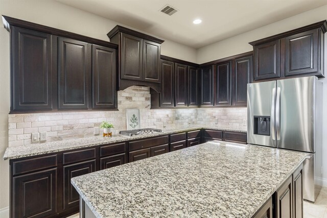 kitchen featuring appliances with stainless steel finishes, decorative backsplash, light stone counters, and visible vents
