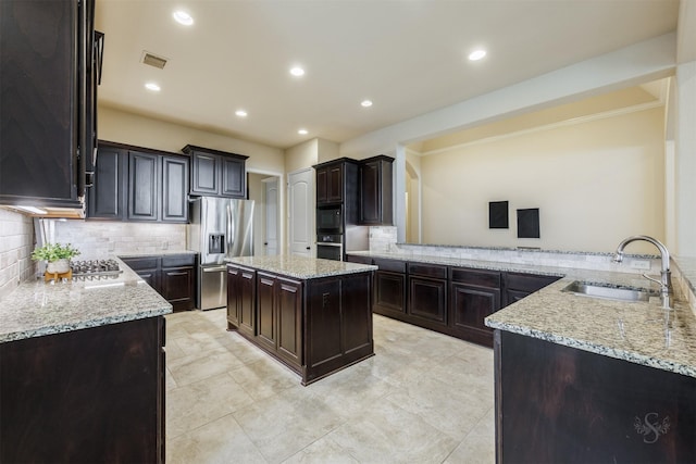 kitchen featuring stainless steel appliances, light stone counters, a sink, and tasteful backsplash