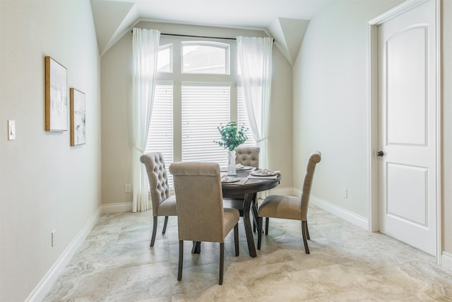 dining space featuring baseboards and vaulted ceiling