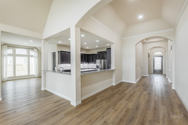 4903 Cancun Hills Ct, Fulshear, TX 77441 - kitchen featuring stainless steel fridge, arched walkways, light stone countertops, light wood-style flooring, and high vaulted ceiling