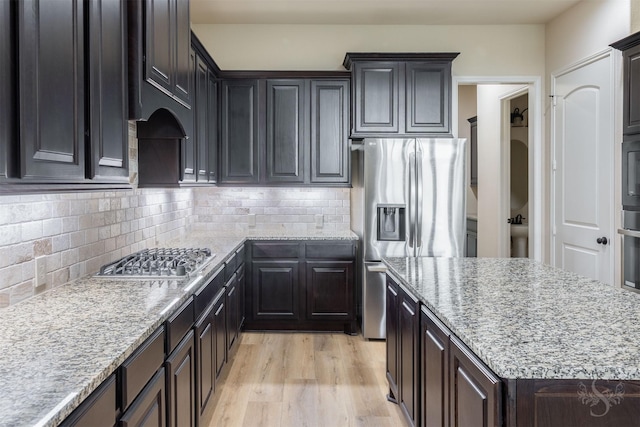 4903 Cancun Hills Ct, Fulshear, TX 77441 - kitchen with appliances with stainless steel finishes, tasteful backsplash, light stone counters, and light wood-style floors