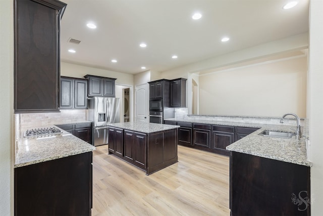 4903 Cancun Hills Ct, Fulshear, TX 77441 - kitchen with stainless steel appliances, backsplash, light stone counters, light wood-style flooring, and recessed lighting
