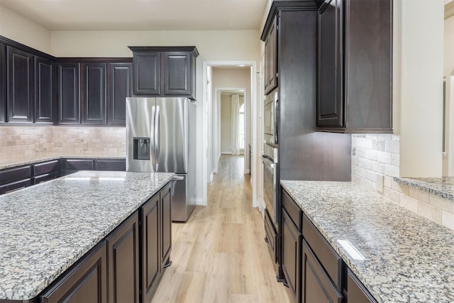 4903 Cancun Hills Ct, Fulshear, TX 77441 - kitchen featuring stainless steel appliances, light wood-style floors, light stone countertops, and decorative backsplash