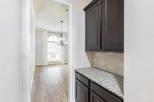 4903 Cancun Hills Ct, Fulshear, TX 77441 - kitchen with light wood finished floors, backsplash, a chandelier, dark brown cabinetry, and light stone countertops
