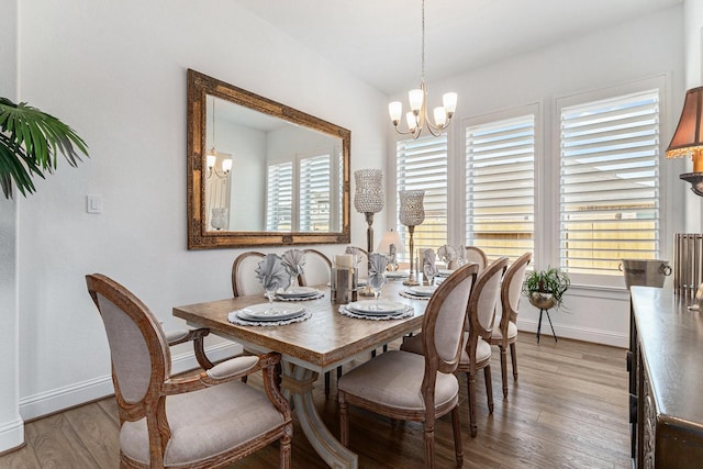 dining area with light wood-style floors, a healthy amount of sunlight, baseboards, and an inviting chandelier