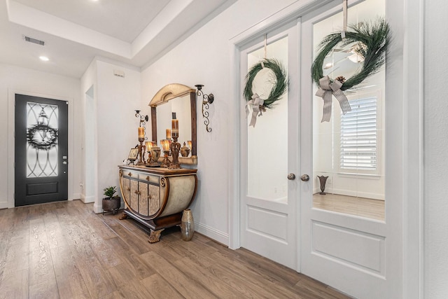 foyer entrance featuring baseboards, visible vents, wood finished floors, and french doors