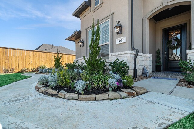 view of exterior entry featuring fence and stucco siding