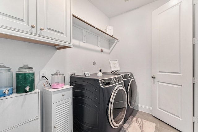 washroom with washing machine and dryer, cabinet space, baseboards, and light tile patterned floors