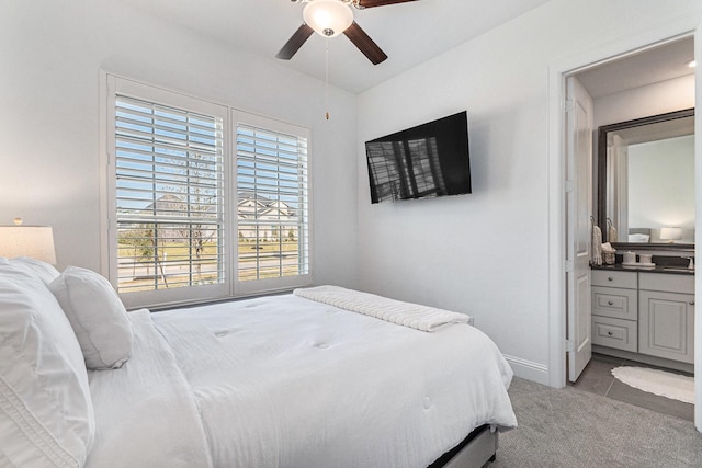 carpeted bedroom featuring ensuite bathroom, a ceiling fan, and baseboards