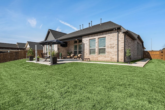 back of house featuring a yard, a fenced backyard, a patio, and brick siding