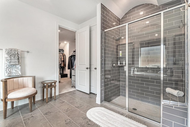 bathroom featuring a shower stall, baseboards, and a spacious closet