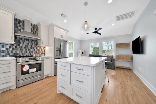 kitchen with wall chimney exhaust hood, visible vents, appliances with stainless steel finishes, and backsplash