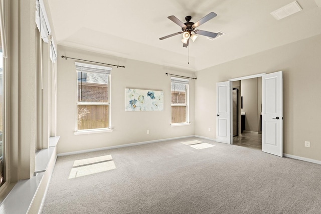 unfurnished bedroom with ceiling fan, a raised ceiling, carpet flooring, and baseboards