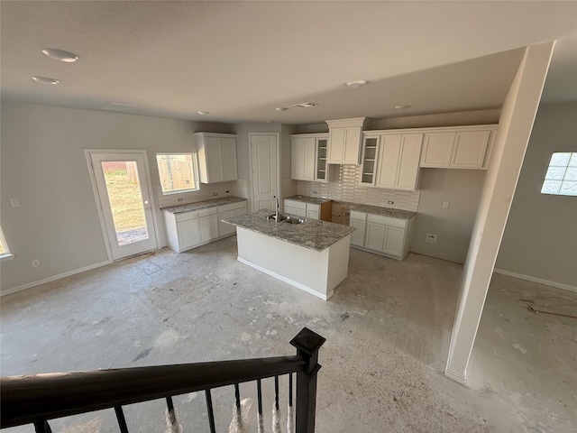 2011 Sunflower Ct, Sugar Land, TX 77498 - kitchen featuring a sink, backsplash, an island with sink, white cabinets, and baseboards
