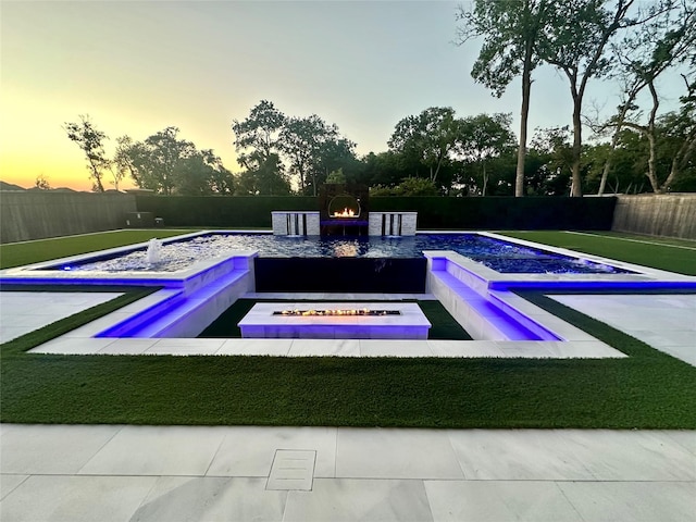 pool at dusk with a fenced in pool and a fenced backyard