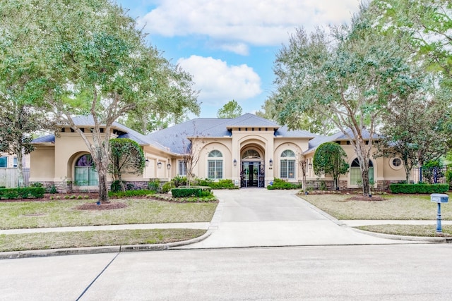 mediterranean / spanish home with stucco siding, concrete driveway, and french doors