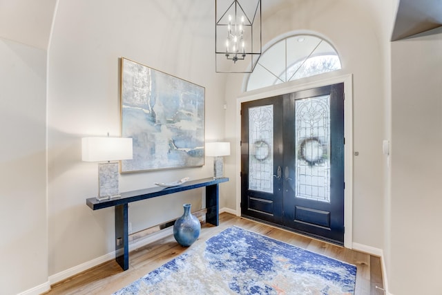 foyer entrance featuring a notable chandelier, wood finished floors, and french doors