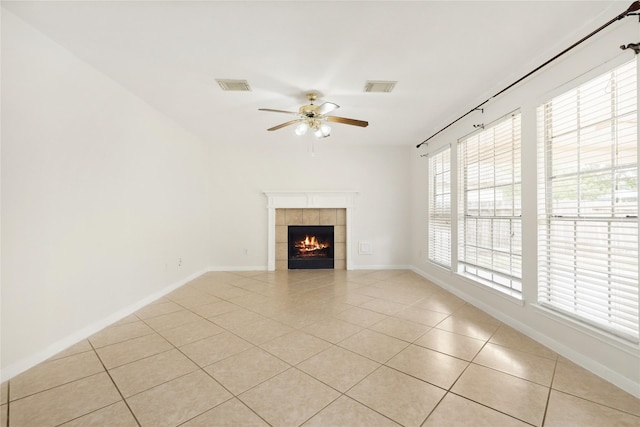 unfurnished living room with visible vents, ceiling fan, a tiled fireplace, and light tile patterned floors