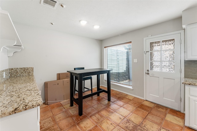 dining area with stairway, stone tile flooring, visible vents, and baseboards