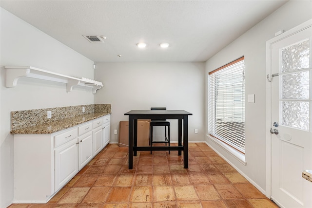 kitchen featuring light stone counters, open shelves, visible vents, white cabinetry, and baseboards