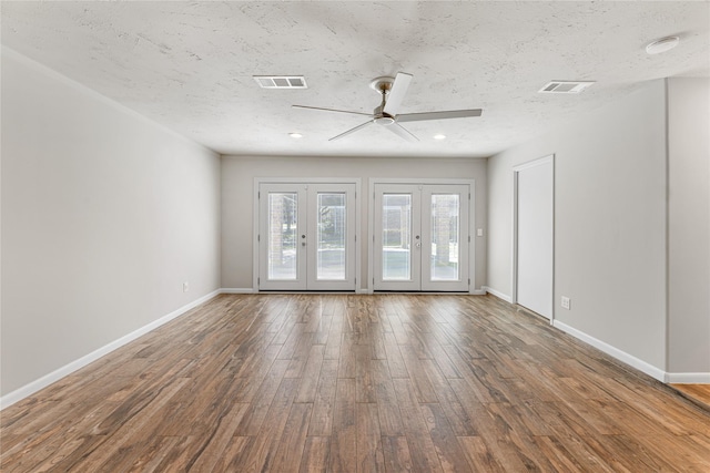 empty room with baseboards, visible vents, wood finished floors, a textured ceiling, and french doors