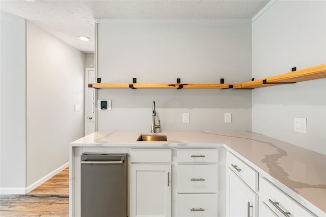 kitchen with a textured ceiling, a sink, white cabinetry, light wood-style floors, and open shelves