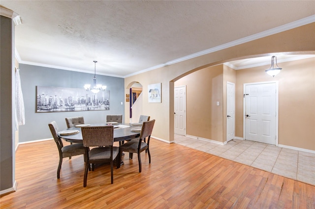 dining space with arched walkways, light wood finished floors, a textured ceiling, and baseboards