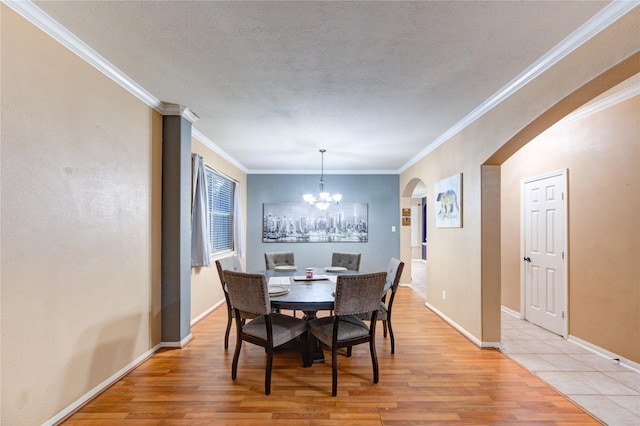 dining room featuring a chandelier, arched walkways, crown molding, and light wood-style floors