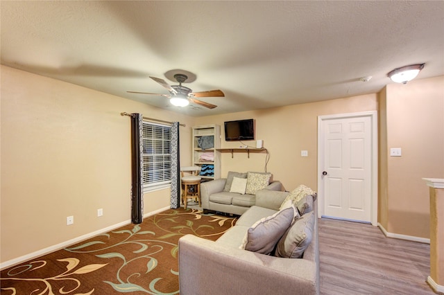 living room featuring a ceiling fan, baseboards, and wood finished floors