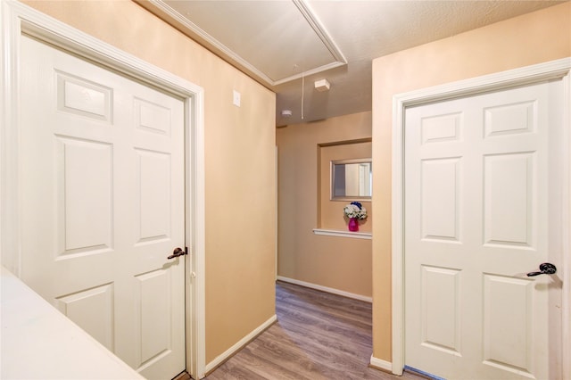 hallway featuring attic access, baseboards, and wood finished floors