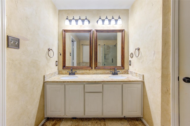 bathroom with double vanity, a shower, and a sink