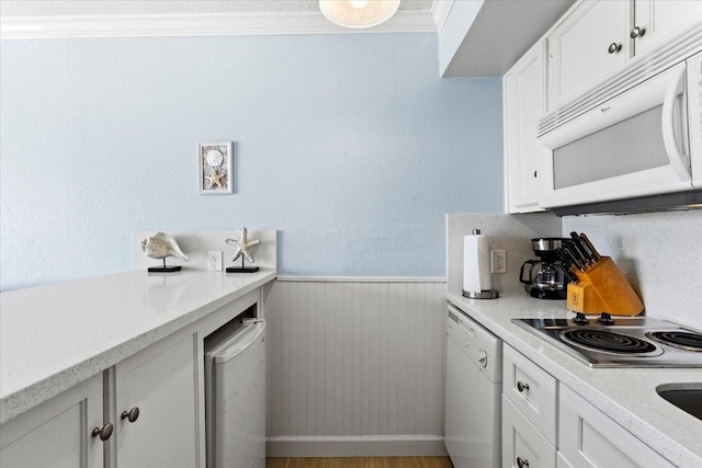 kitchen with white appliances, wainscoting, and white cabinetry