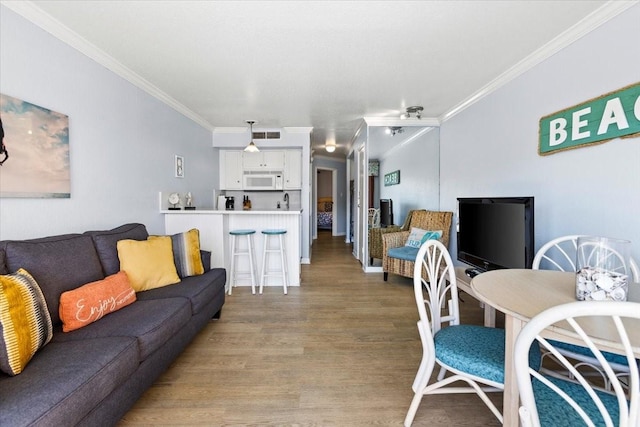 living area featuring light wood-type flooring, visible vents, and crown molding